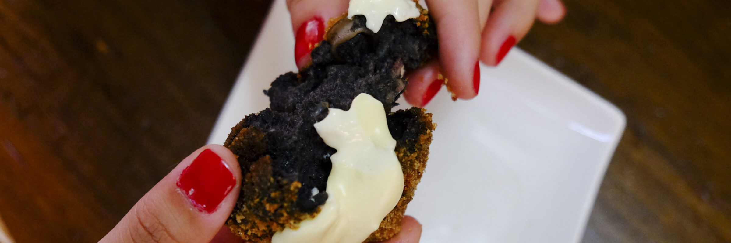 Croqueta de arroz negro con alioli abierta por la mitad